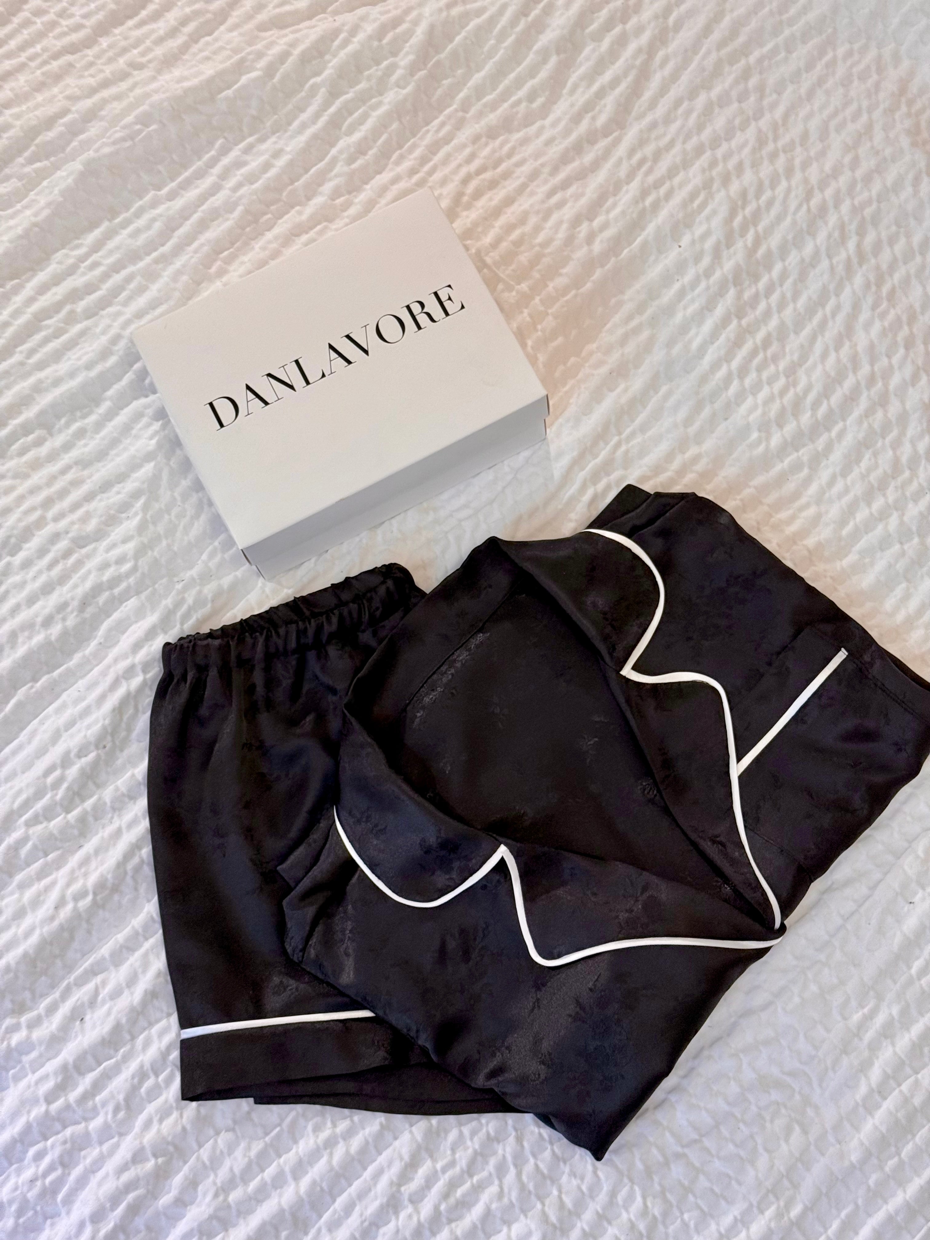Black pajama set with white piping on a textured white surface, featuring the brand 'Danlavor'.